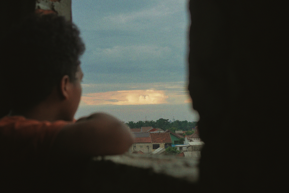 Person looking thoughtfully out the window of their home, representing the feeling of being stuck when considering selling.