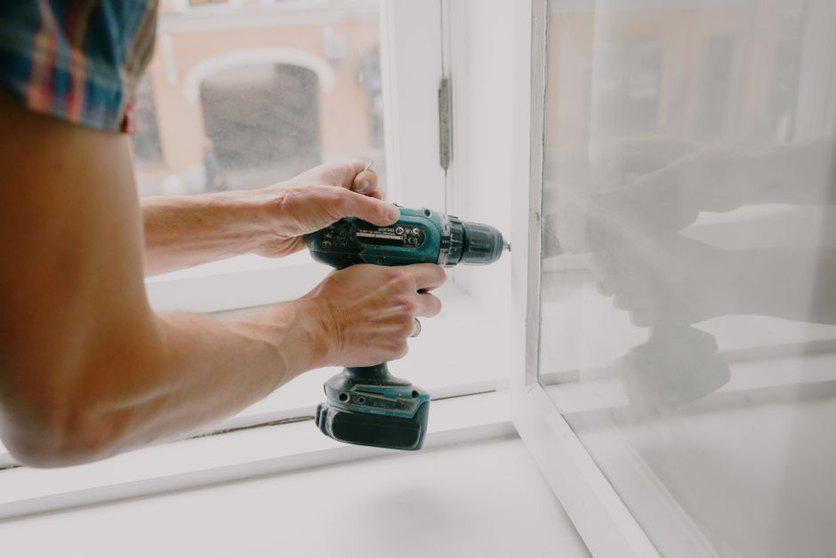 A professional contractor in clean work gear carefully installing spray foam insulation in the attic of a residential home.
